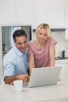 Happy couple using laptop in the kitchen at home