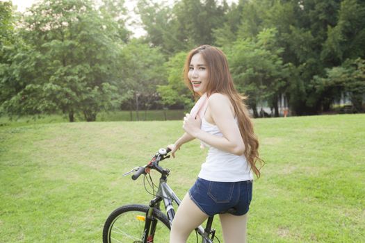 Woman riding an exercise bike in the park. On the lawn in the evening.