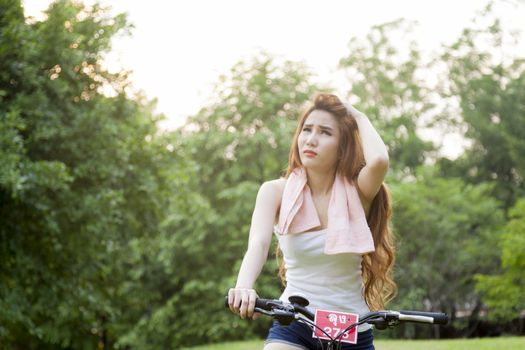 Woman riding an exercise bike in the park. On the lawn in the evening.