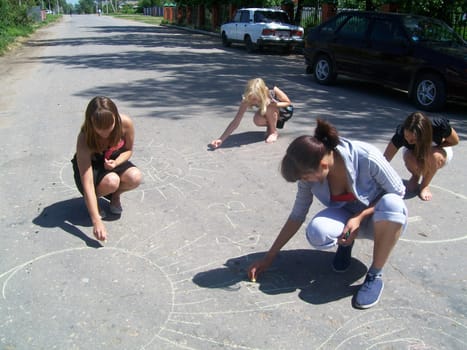 Children draw on the asphalt with crayons