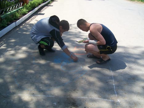 Children draw on the asphalt with crayons