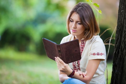Young attractive woman reading e-book in summer park