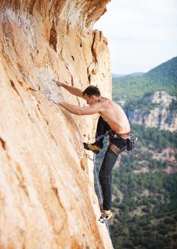Young male rock climber on a face of a cliff