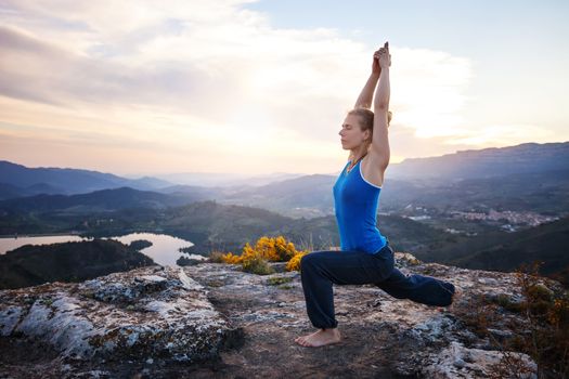 Young Caucasian woman working out on a rock against valley view