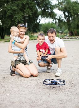 Young family with two boys playing with RC quadrocopter toy