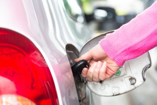 Closeup of a hand opening the fuel tank of  an automobile with a key. 