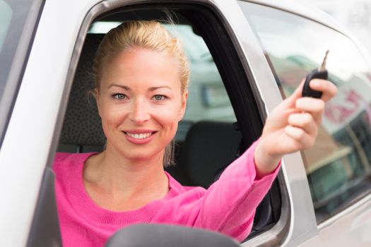 Cheerful lady holding car key in her hand. Focus on woman's eyes.