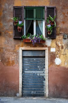 Window with flowers and blinds, old streets of Rome, Italy