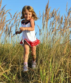Laughing Happy little girl running on meadow with sunset. Summer 