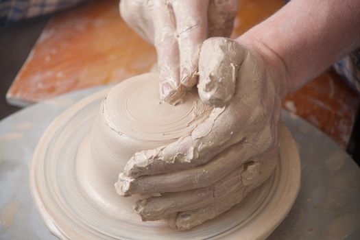 Hands of a potter, creating an earthen jar on the circle