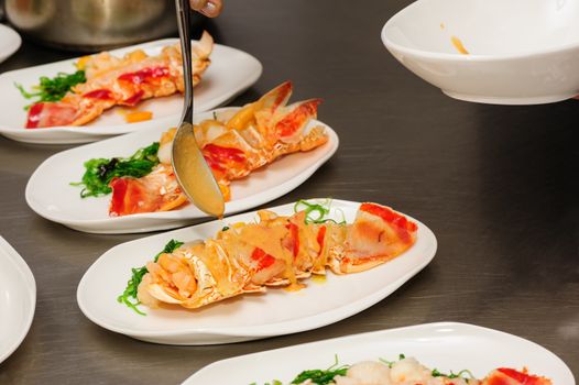 Decorating of prepared lobsters on plates, pouring the sauce