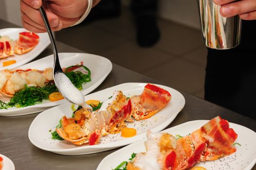 Decorating of prepared lobsters on plates, pouring the foam sauce