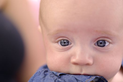 Close-up of a six month baby girl with rosy cheeks nibbling her dres