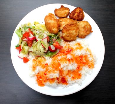 chicken on a plate with rice and salad, shot from above