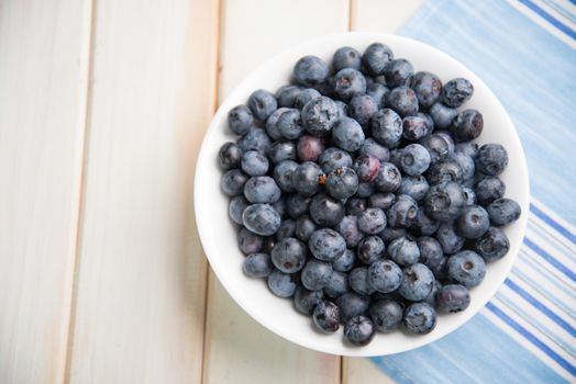 Fresh organic blueberries on plate over white background retro kitchen table