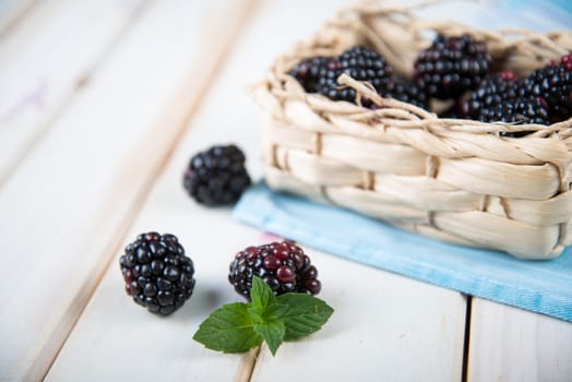 Fresh organic blackberries in  basket and blue kitchen cloth on white background retro kitchen table