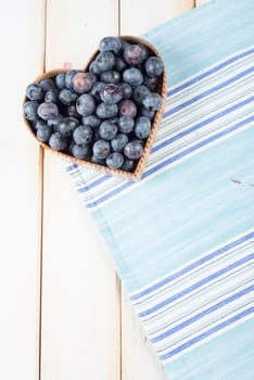 fresh organic blueberries in heart style shape basket and blue kitchen cloth on white background retro kitchen table