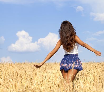 Beautiful young woman in a wheat golden field