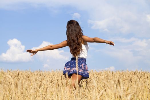 Beautiful young woman in a wheat golden field