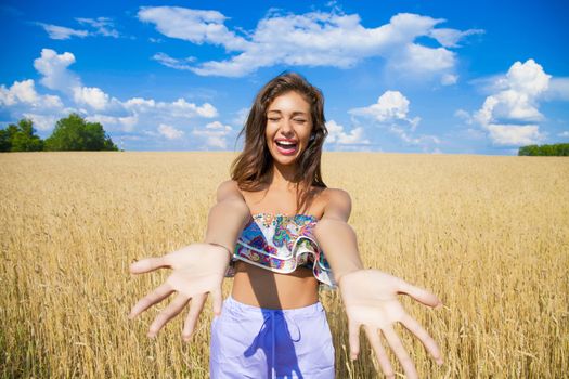 Beautiful young woman in a wheat golden field