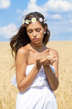 Beautiful young woman in white dress on wheat golden field