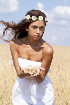 Beautiful young woman in white dress on wheat golden field