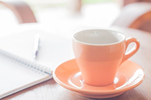 Orange coffee cup with pen and notebook, stock photo