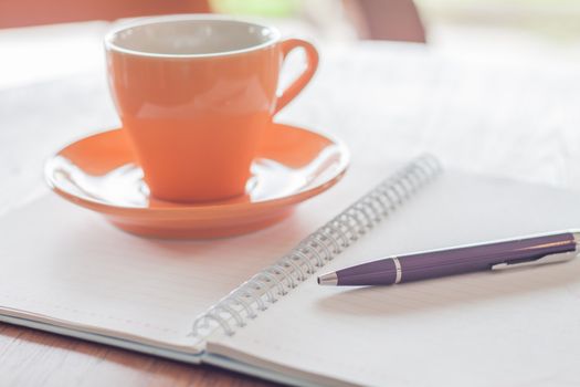 Coffee cup, pen and notebook on wooden table, stock photo