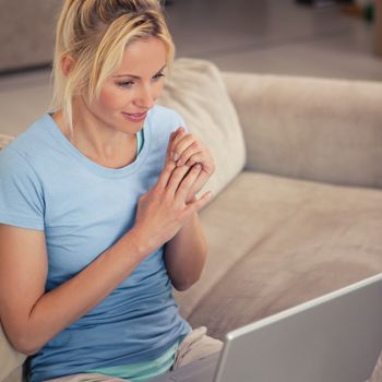 Smiling woman using laptop in the living room at home