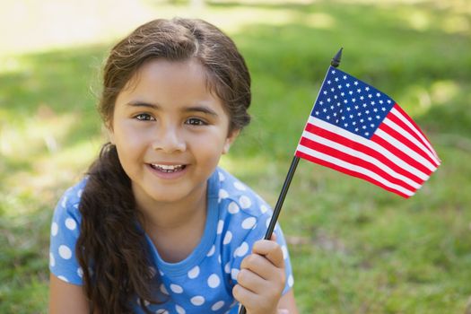 Close-up portrait of a young girl holding the American flag at the park