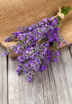 lavender flowers in a basket with burlap on the wooden background