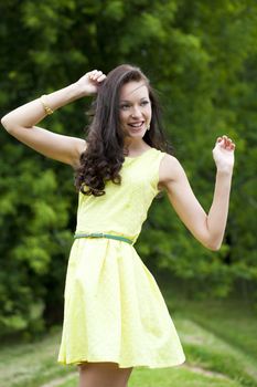 Beautiful young woman in green dress, against green of summer park