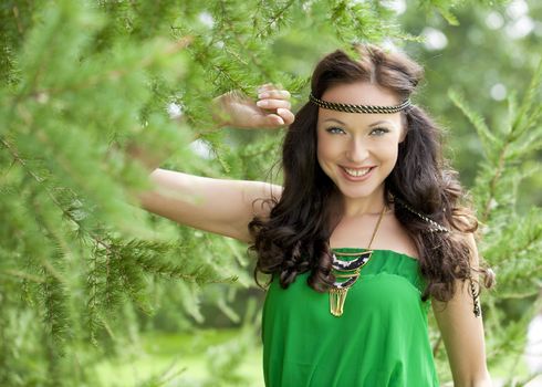 Beautiful young woman in green dress, against green of summer park