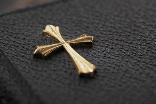 Gold color cross on the cover of an old pocket-sized bible.