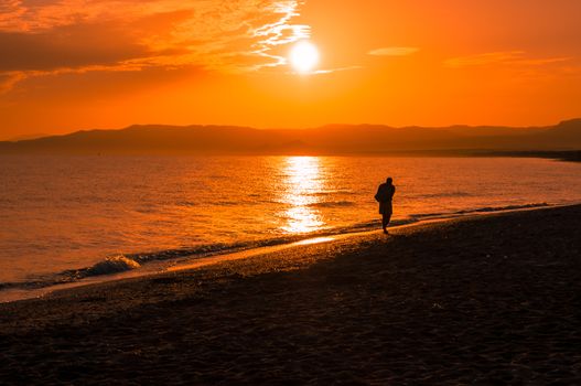 a man walking on the beach at the sunrise
