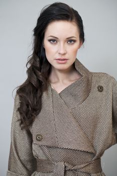 Beautiful young woman in autumn coat against gray background