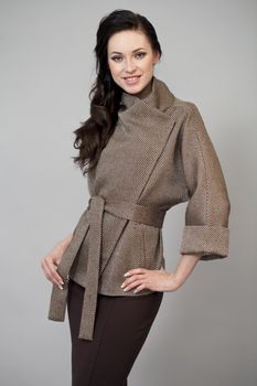 Beautiful young woman in autumn coat against gray background