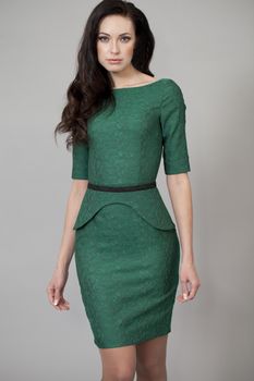 Young beautiful woman in green dress posing on grey background