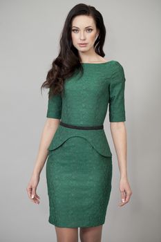 Young beautiful woman in green dress posing on grey background