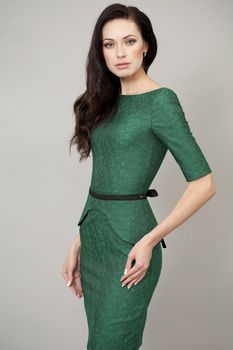 Young beautiful woman in green dress posing on grey background