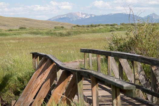 This bridge in the Arapaho National Wildlife Refuge crosses a small creek in a riparian area, in the high plains region known as North Park, in the Colorado Rocky Mountains.