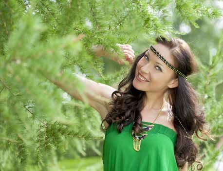 Beautiful young woman in green dress, against green of summer park