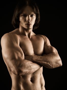 Photo of an attractive young muscular man with no shirt posing with his arms crossed.