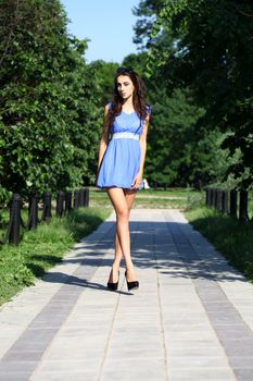 Beautiful young woman walking on the summer park