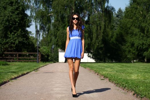 Beautiful young woman walking on the summer park