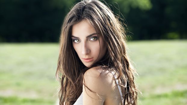 Portrait of a beautiful sexy young brunette woman in summer park