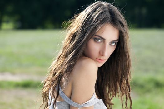 Portrait of a beautiful sexy young brunette woman in summer park