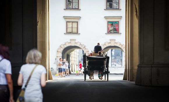 VIENNA, AUSTRIA - AUGUST 4, 2013: Traditional horse-driven carriage with tourists at Hofburg palace, Vienna, Austria