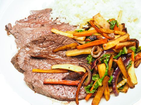 Seasond and fried steak with rice and vegetables on white plate