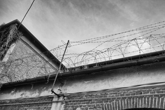 Barb wire on top of a wall, with tower on the left, black and white hdr image